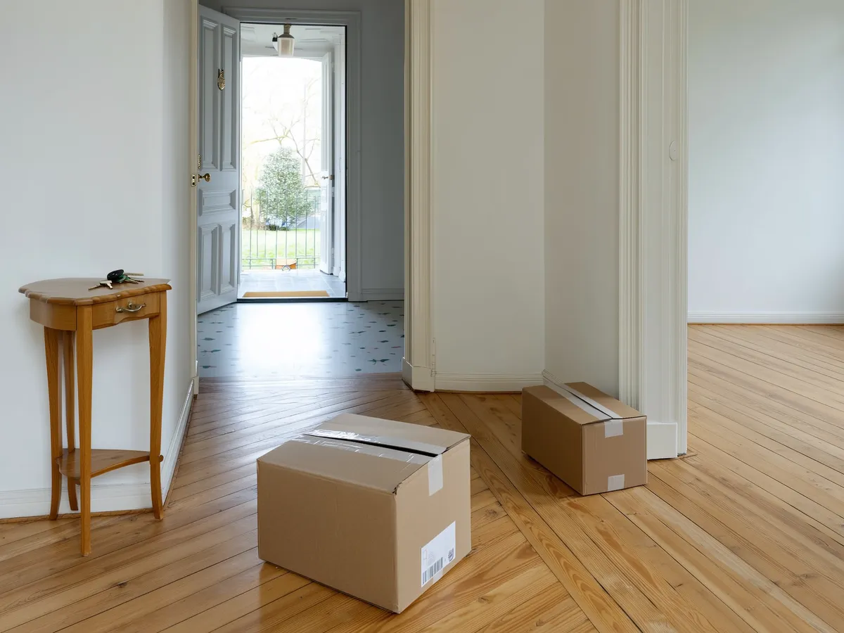 Heller Eingangsbereich eines Hauses mit Schlüsselbund auf einer Konsole und Umzugskartons, Symbolbild für den Ablauf beim Hauskauf